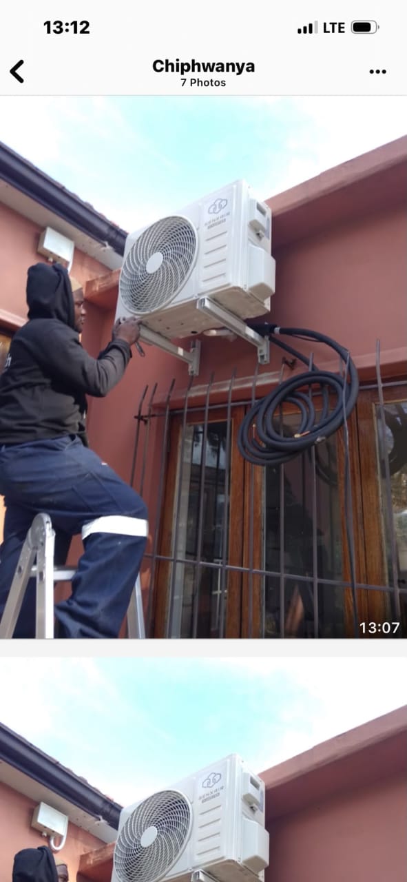 Technician mounting an outdoor condenser bracket on an exterior wall