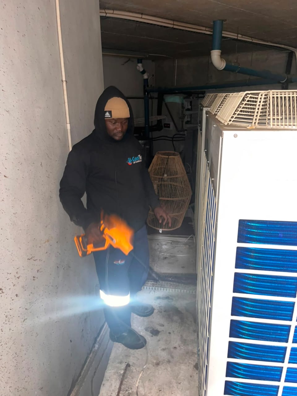 Technician pressure-cleaning the coils of a large commercial cooling unit