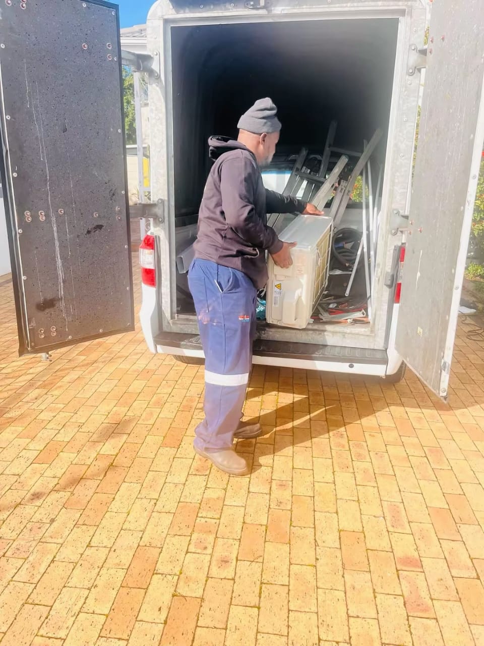 Technician offloading an indoor air conditioner unit from the service vehicle
