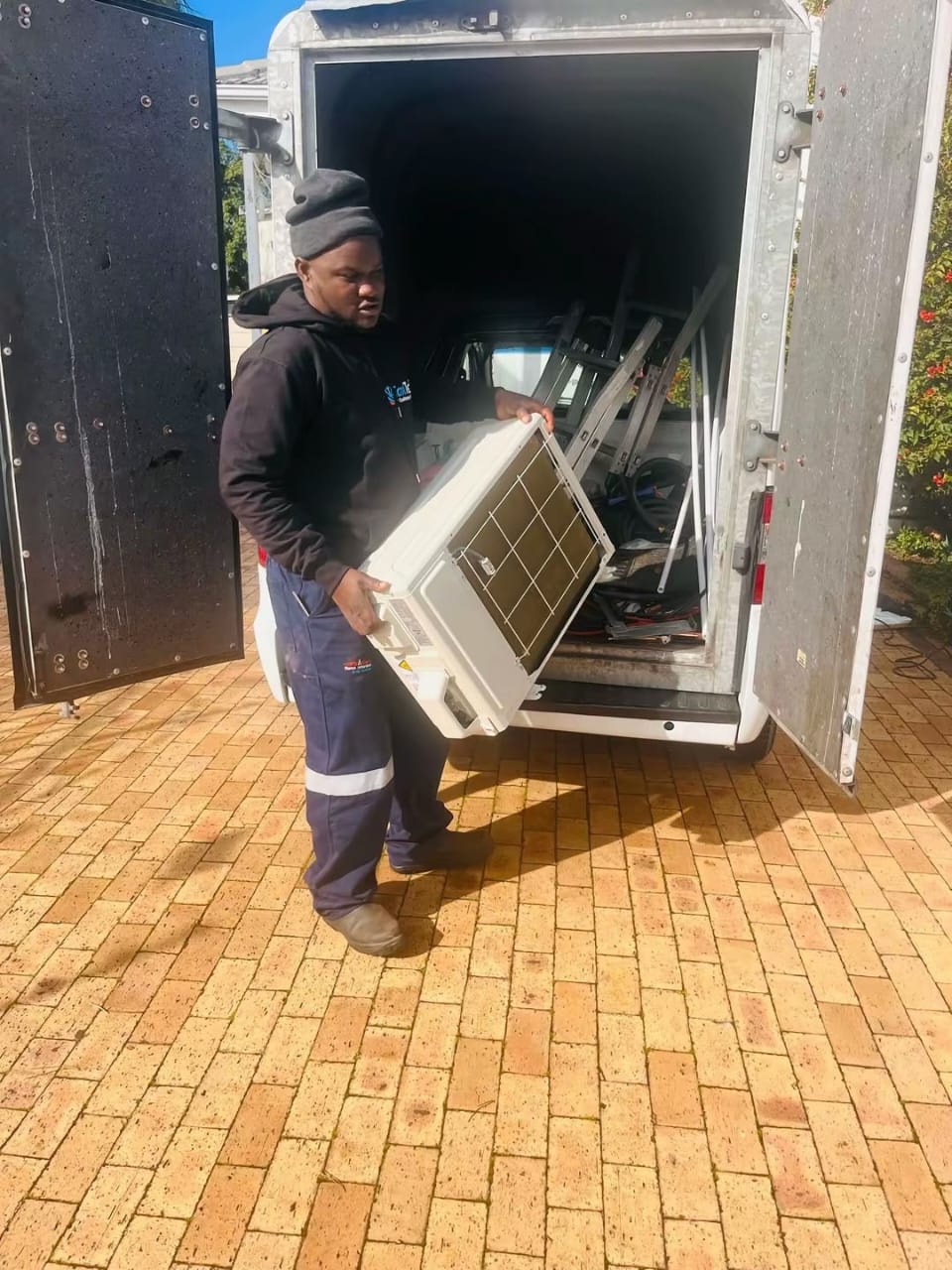 Mike Cooling Solutions technician carrying an indoor air conditioner unit to site